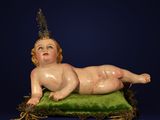 a statue of a baby laying on a green pillow