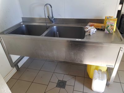 a stainless steel sink in the corner of a kitchen