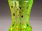 a green glass vase with black spots on it
