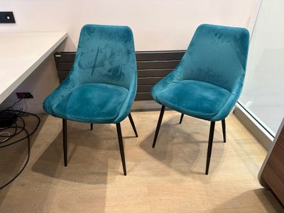 two blue chairs sitting next to each other in front of a desk