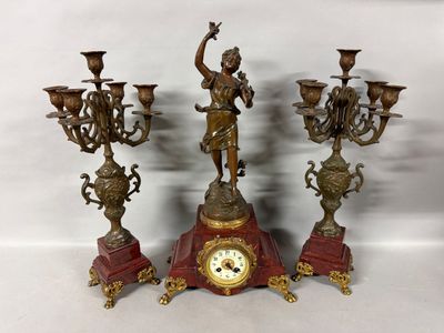 three candlesticks and a clock on a table