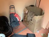 a cardboard box with a teddy bear in it next to a chair and luggage