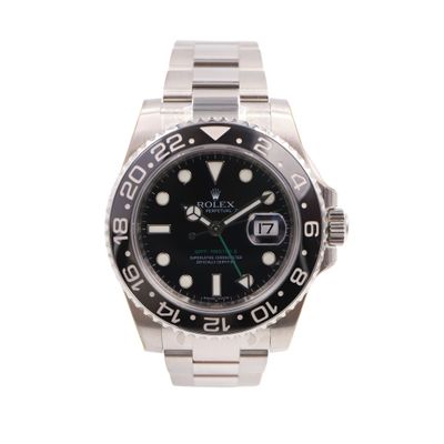 rolex watch with black dial and green hands on a stainless steel bracelet