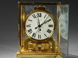 a gold clock with roman numerals and a glass case