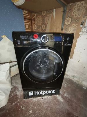 une photo d'une machine à laver noire dans un coin d'une pièce