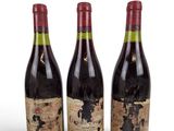 trois bouteilles de vin posées les unes à côté des autres sur une surface blanche