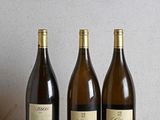 three bottles of wine are lined up on a wooden table
