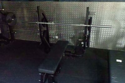 une salle de sport avec un banc, des poids et d'autres équipements