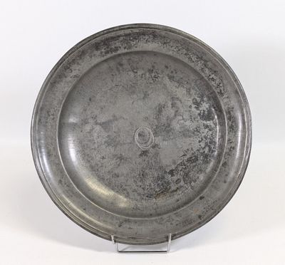 plat en argent sur un support posé sur une surface blanche, avec un fond blanc