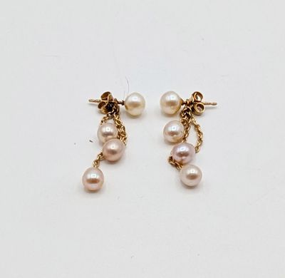 two pearl earrings with gold chains on a white surface