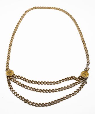 gros plan d'une chaîne en or sur laquelle se trouve une pièce de monnaie