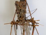 une sculpture représentant une femme assise au sommet d'un poteau en bois