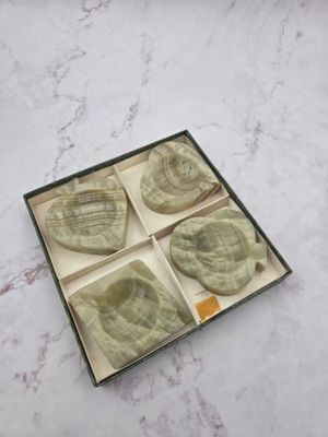 quatre morceaux de savon dans une boîte posée sur un plan de travail en marbre