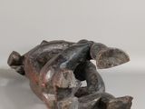 sculpture of a hand holding a piece of wood on a white surface