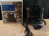 une boîte contenant divers objets posée sur une table, parmi lesquels une cafetière et un chargeur