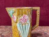 a yellow pitcher with pink flowers on it on a table