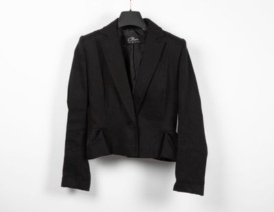 black blazer jacket hanging on a hanger against a white wall