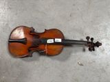 un gros plan d'un violon posé par terre, sur lequel est accrochée une étiquette
