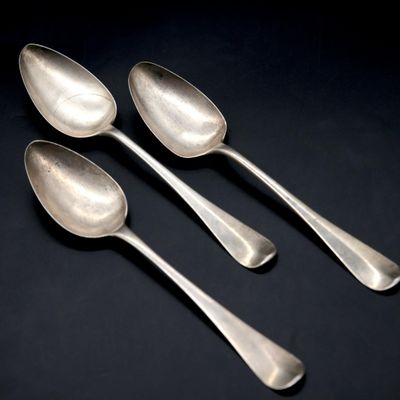 three silver spoons sitting on top of a table next to each other