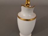 a white and gold vase with a gold lid