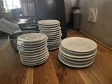 several white plates stacked on top of each other on a wooden table