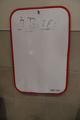 un tableau blanc sur lequel sont inscrits des mots, dans des toilettes publiques