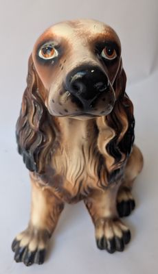 a figurine of a dog sitting on a white surface