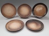 quatre assiettes marron posées les unes à côté des autres sur une surface blanche
