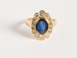 gros plan d'une bague en or avec un saphir et des diamants