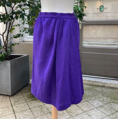 purple skirt on a mannequin stand in front of a potted plant