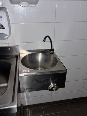 un lavabo en acier inoxydable et un sèche-mains en acier inoxydable dans des toilettes publiques
