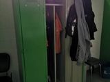 a green locker with clothes hanging on it in a room