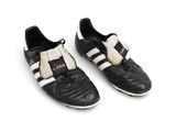 une paire de chaussures de foot noires et blanches posées sur une surface blanche
