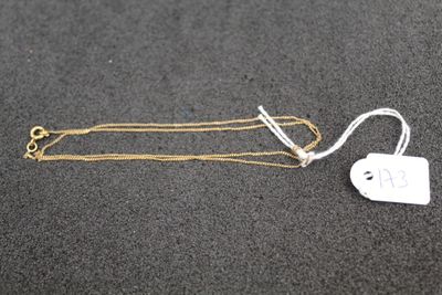 a gold necklace with a tag attached to it on a black surface