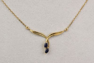 un collier plaqué or orné d'une pierre bleue, monté sur une chaîne en or