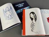 three books on a table with a drawing of a woman