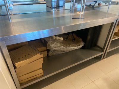 un grand plan de travail en inox dans une cuisine, sur lequel sont posées des boîtes