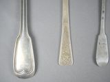 three silver spoons and a fork on a gray surface