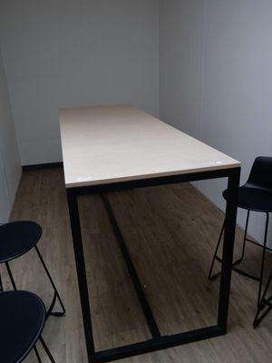 des tables et des chaises dans une pièce avec un parquet et des murs blancs
