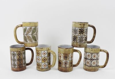 Plusieurs tasses à café sont alignées sur une surface blanche