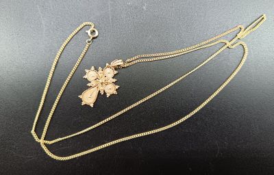 un collier en or orné d'une croix et d'une fleur