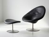 une chaise noire et un pouf noir dans une pièce blanche