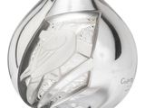 a silver vase with a bird on it on a white surface