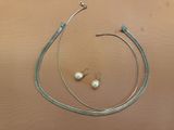 a silver necklace and a pair of pearl earrings on a table