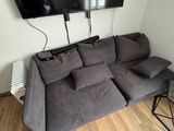 a couch with pillows and a tv mounted on the wall