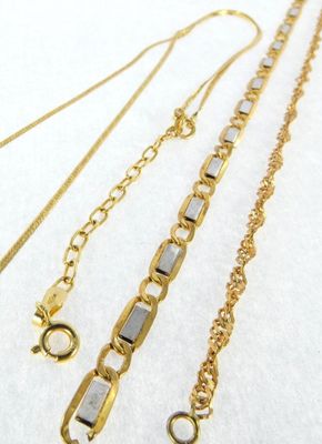 three different types of gold chains on a white surface