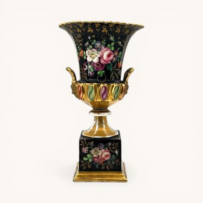 un vase noir orné de fleurs, posé sur un socle