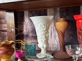 many vases and glasses on a shelf in a room