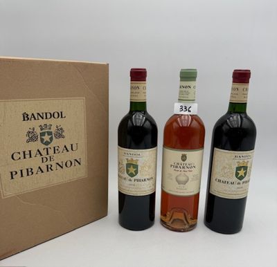 trois bouteilles de vin sont posées à côté d'un carton sur une surface blanche