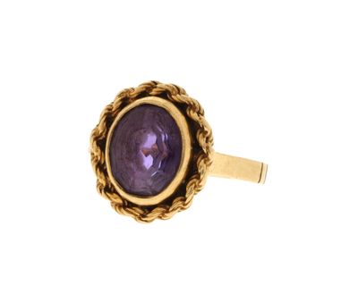 gros plan d'une bague en or avec une pierre violette